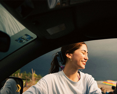 young woman looking out of car window at sunset