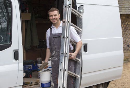 A smiley decorator gets his equipment out of his mid-sized van ready to work.