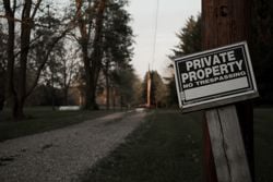 A 'private property, no trespassing' sign on a wooden post