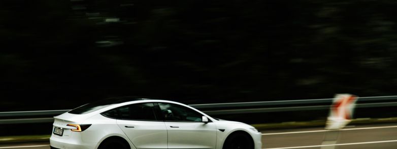 A modern electric car in motion on a highway, showcasing speed and innovation.