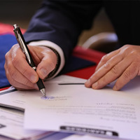a person signs a document with a pen