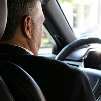 man in black suit driving car