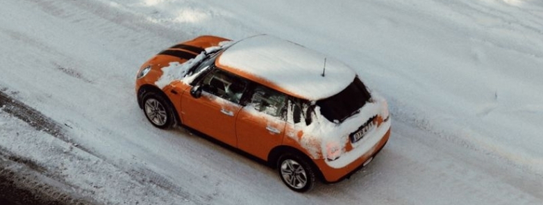Aerial view of an orange car driving on a snowy street in Jönköping, Sweden.