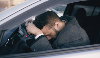Young bearded business man sitting in car very upset and stressed after failure and moving in traffic jam