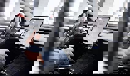 Person sitting in a Tesla with the large touchscreen visible