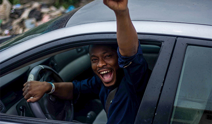 young driver in the car looking happy with his arm raised out of the window in joy