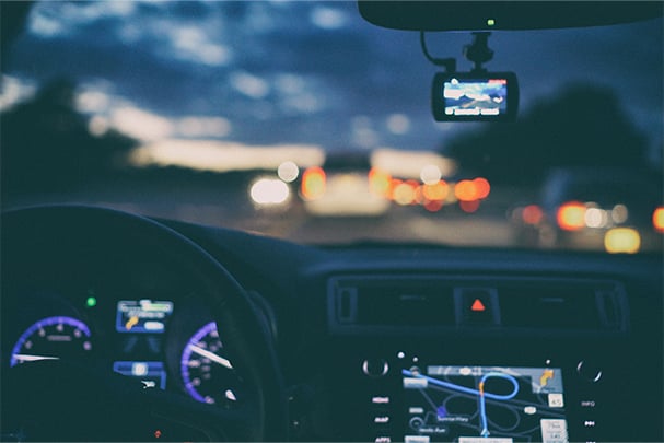 A sunset from the view point of behind a car steering wheel.