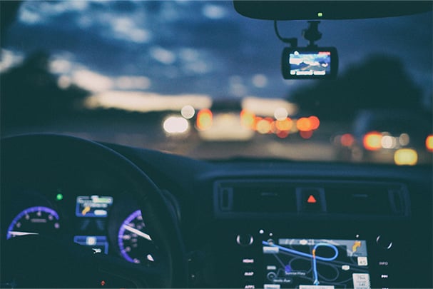 A sunset from the view point of behind a car steering wheel. 