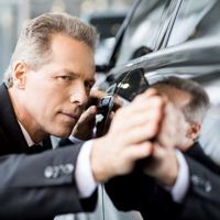 man inspecting vehicle for damage