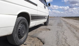 car driving over pothole
