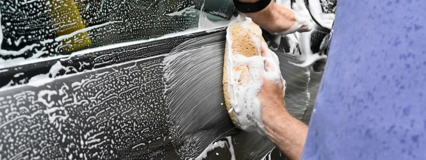 a man washing a car with sponge