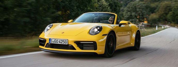 yellow porsche driving on the road
