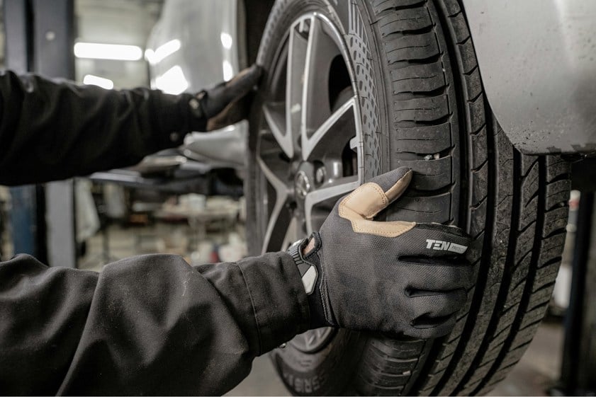 Mechanic with gloves on attaching a tyre to a car
