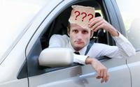 car driving holding sign with question marks