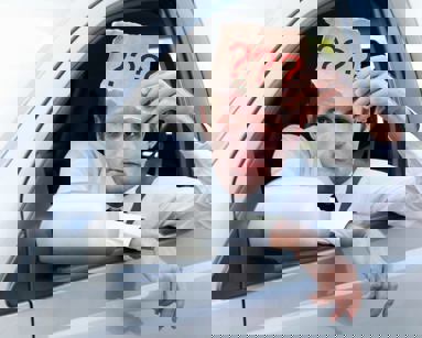 car driving holding sign with question marks