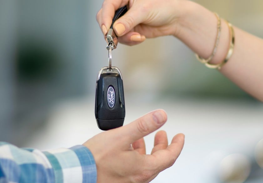 a person handing a car key to another person