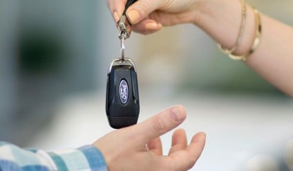 a person handing a car key to another person