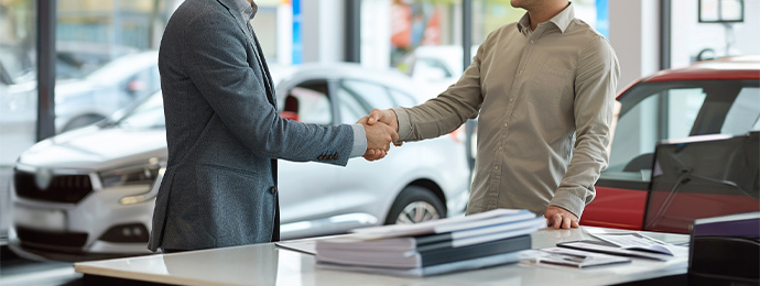 Two men shaking hands at a UK car dealership after agreeing a lease deal