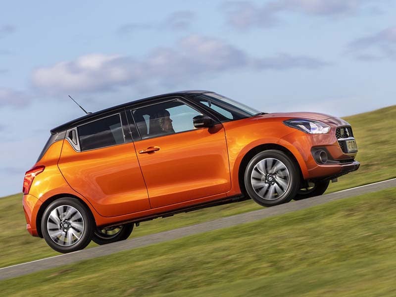 Orange Suzuki Swift climbing a hill