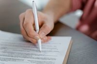 Detailed view of a hand writing a signature on an official document with a ballpoint pen