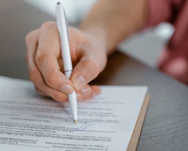 Detailed view of a hand writing a signature on an official document with a ballpoint pen
