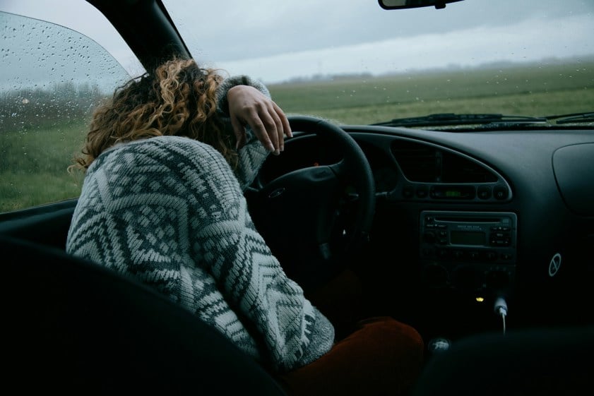 person in grey and white sweater driving car