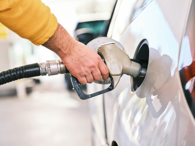 Person filling a white car with fuel