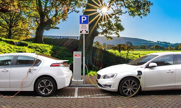 two white electric cars charging via a public charger