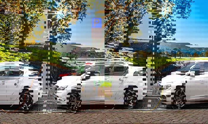two white electric cars charging via a public charger