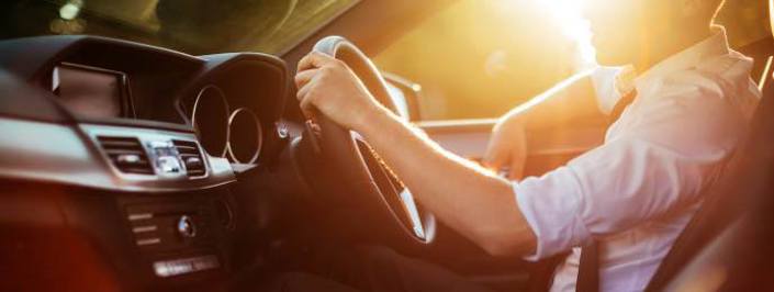 man driving his car with sunset behind
