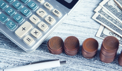A calculator, pen, and money on a table