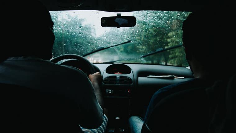 Two Men Inside Moving Vehicle with rain outside
