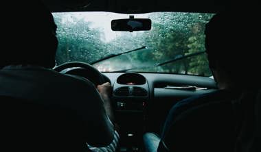 Two Men Inside Moving Vehicle with rain outside