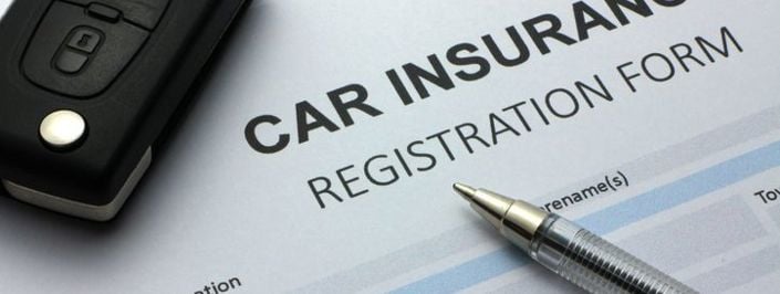 Car fob lying atop car insurance registration form