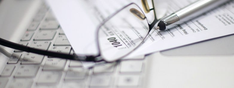 glasses and paperwork on laptop