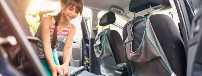 young woman vacuuming the back of a car