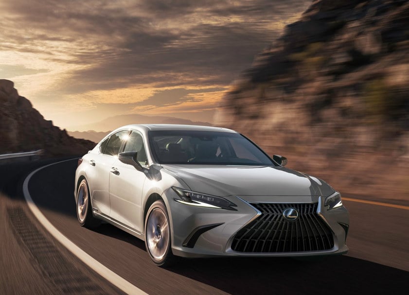 Side-front view of a Lexus ES Saloon driving on a country road with rocky hills in the background