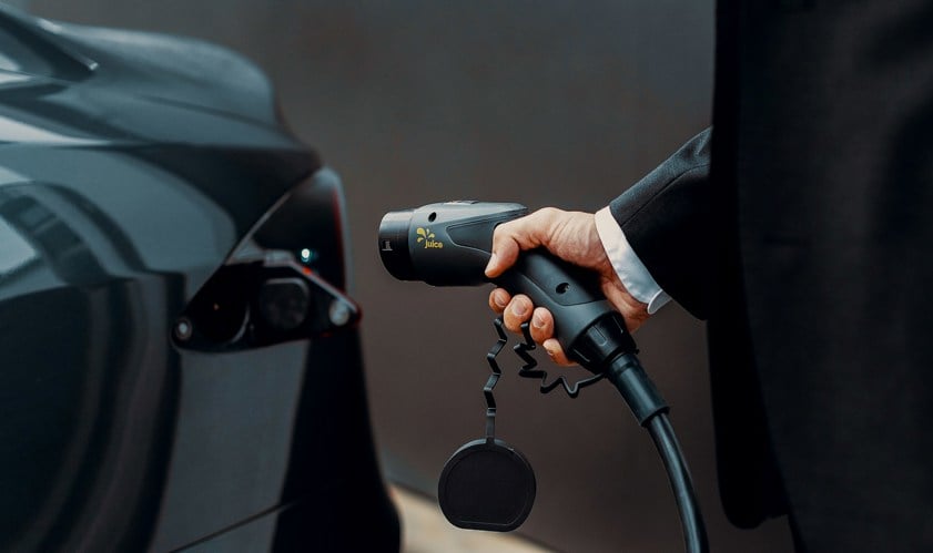 Person in black suit holding an EV charger