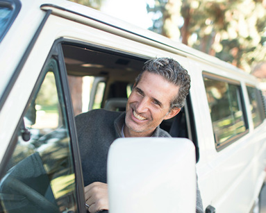man in grey sweater leaning on van window