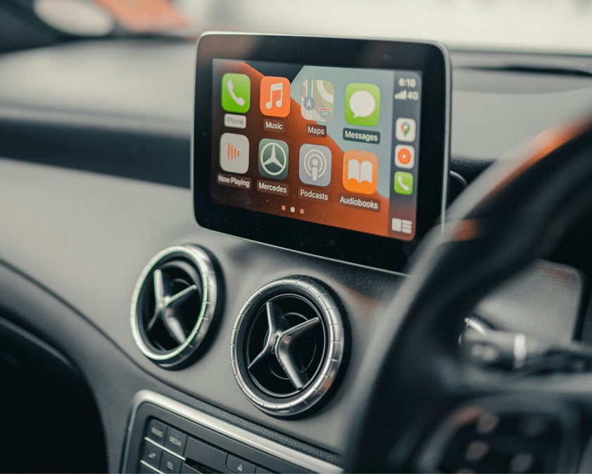 Car interior showing a close-up of a dashboard-mounted infotainment screen with Apple CarPlay