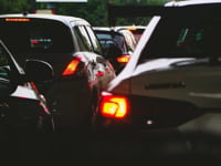 A close-up view of a traffic jam showcasing rear car lights glowing at dusk