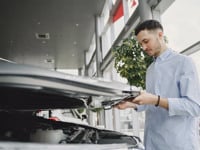 Man in a shirt opening a car bonnet