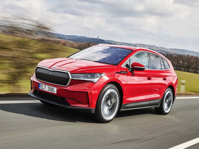 red skoda enyaq iv driving on the road