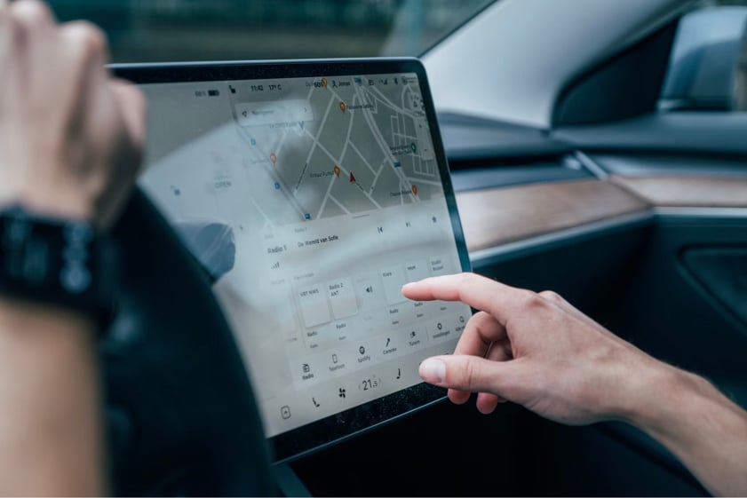 A man using a Teslas touchscreen infotainment system