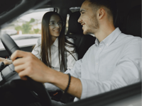 A smiling couple driving together in a car, enjoying their time on the road.