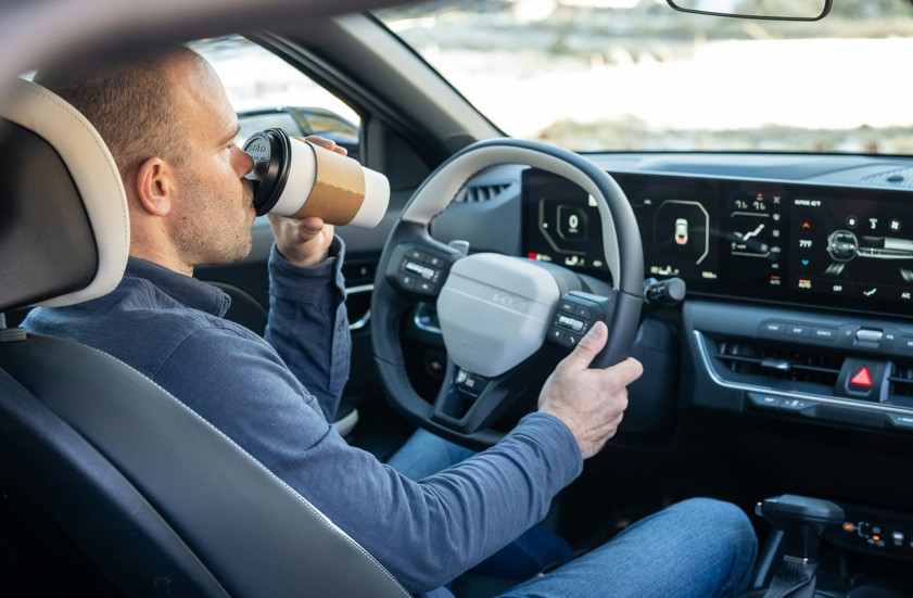 a man driving a car with a cup in this hand