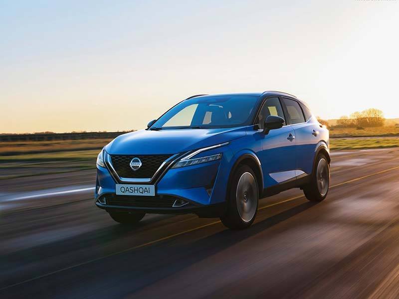 blue nissan qashqai driving on the road in sunset