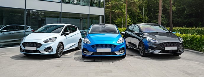 Ford Fiesta range including white, blue and grey hatchbacks parked outside a showroom