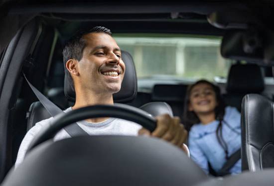 Happy father driving with his daughter in the car and smiling