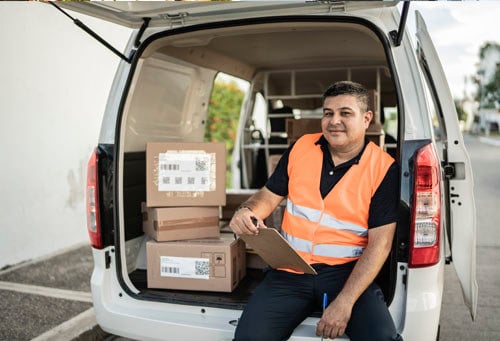 Portrait of delivery person with van truck outdoors